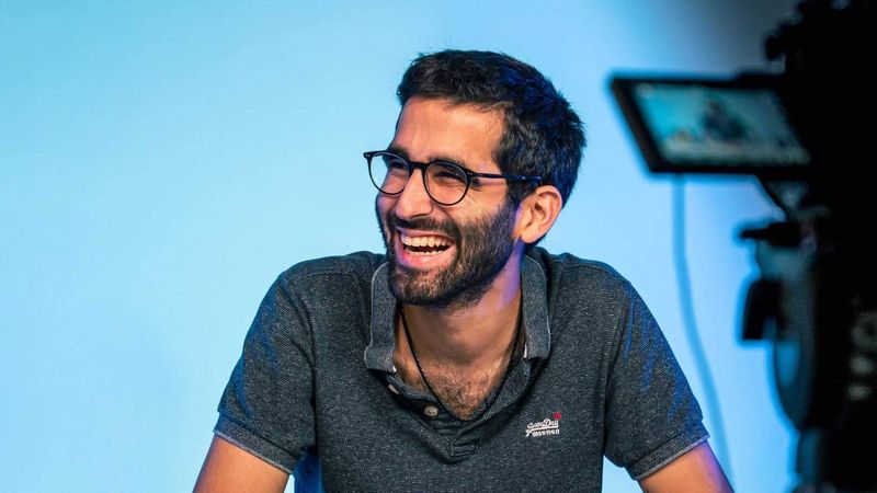 Omar Belkaab, hilare, sur un plateau de tournage face à une caméra